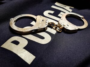 kajdanki leżą na koszulce z napisem policja