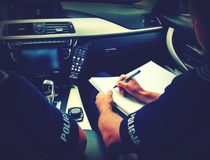 policjanci piszą notatkę w radiowozie