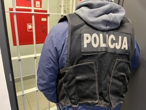 policjant przy kratach celi